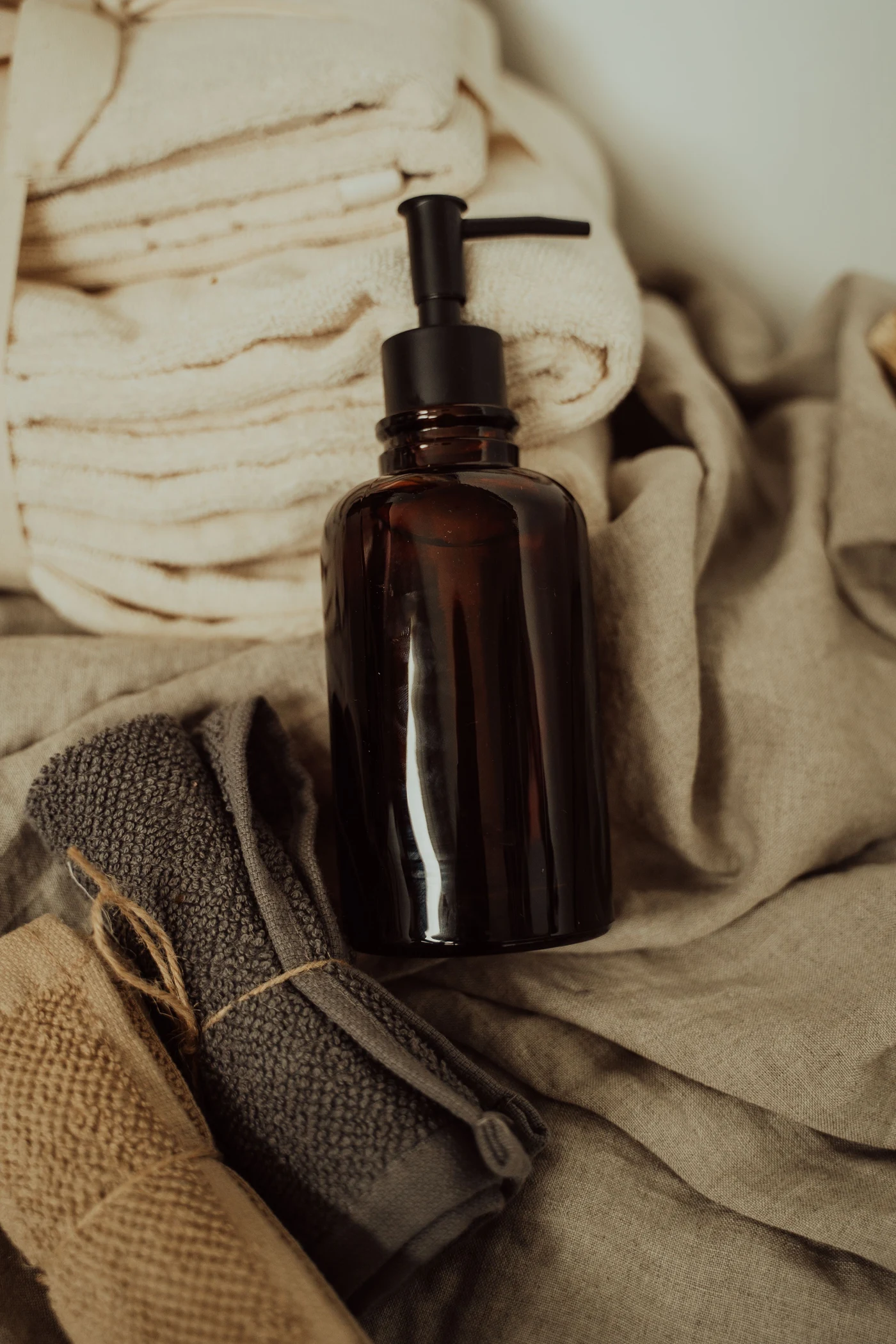 Amber pump bottle beside folded cream towels and linen